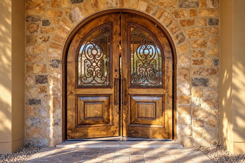 Restored arched entry doors with stained glass and iron scrollwork